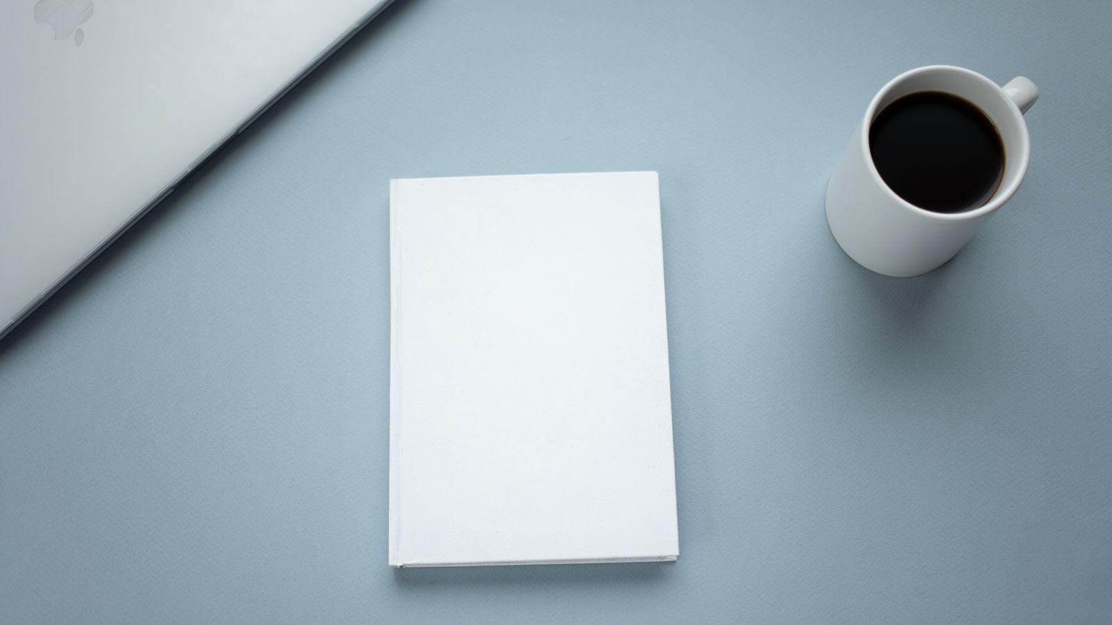Coffee, laptop, and notebook on a desk representing a busy coach short on time for content